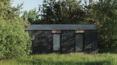 Parlak, siyah bir kulübe canlı yeşil çimenler ve ağaçlarla kaplı, göz kamaştırıcı çağdaş mimari sergileniyor.