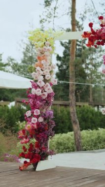 Dikey video. Çok güzel bir çiçek aranjmanı güzel bir manzara, canlı çiçekler ve yemyeşil bir ortam. Düğün kemeri