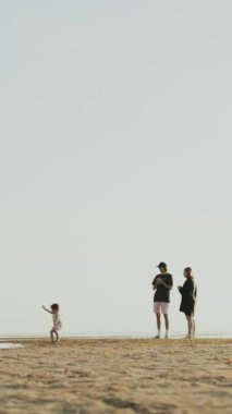 Sahilde bir çocuğun el değmemiş kıyı şeridini zevkle keşfettiği çok güzel bir aile anı. Dikey video