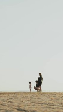 Neşeli bir aile deniz kenarında keyifli bir gün geçirir, parlak mavi bir gökyüzü altında birlikte vakit geçirirler. Dikey video