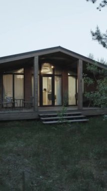 Doğayla çevrili sakin, modern bir kulübe. Hoş bir girişi ve rahat bir iç aydınlatması var. Dikey video