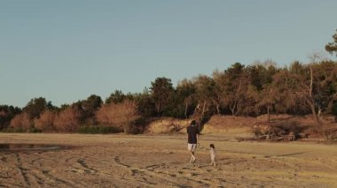 Huzurlu ve huzurlu bir sahil sahnesi güzel bir şekilde ebeveyn ve çocuğu canlandırıyor. Doğanın tadını çıkarıyorlar.