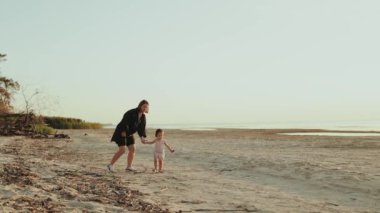 Sevgi dolu bir anne ve küçük çocuğu huzurlu ve huzurlu bir plajda mutlu ve neşeli bir anı paylaşıyorlar.