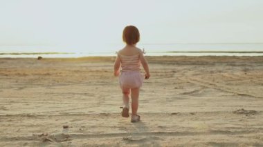 Genç bir çocuk, güzel bir gün batımında huzurlu, resimli bir plajı zevkle keşfeder. Masumiyet ve neşe somutlaştırır.