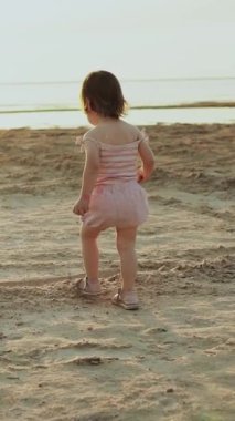 Neşeli bir çocuk, neşeli kumlu sahilleri keşfediyor, doğanın güzelliğini ve tasasız anlarını kucaklıyor. Dikey video.