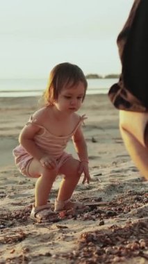 Dikey video. Neşeli, enerjik bir çocuk mutlu bir şekilde kumlu sahili keşfediyor, çocukluk sevincinin özünü yakalıyor.