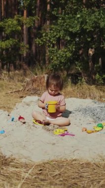 Genç bir çocuk canlı doğayla çevrili iken dışarıda çeşitli eğlenceli aktivitelere katılır. Dikey video. 