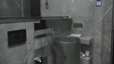 Bu modern banyo koyu mermer kaplamaları ve zarif dokunuşlar için minimalist armatürleri barındırıyor.