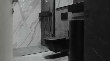 Bu şık banyoda çağdaş bir estetik için parlak mermer tasarımı ve şık siyah eşyalar sergileniyor.