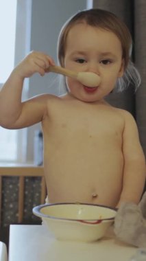 Dikey video. Yemekten zevk alan genç bir çocuk, rahat bir ortamda masumiyetlerini ve meraklarını açıkça gösteriyor.