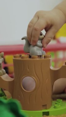 Genç bir çocuk canlı bir oyun yapısında oynarken renkli ve oyuncu bir hayvan figürüyle neşe içinde etkileşime girer. Dikey video.
