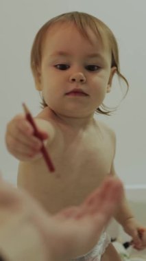Meraklı küçük bir çocuk, banyo zamanında sınırsız yaratıcılıklarını keşfetmek için pastel boyayla sevinçle uzanıyor. Dikey video.