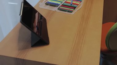Zarif bir şekilde tasarlanmış, bir tablet, bir dizi renkli kırtasiye ve minimalist estetik içeren bir masa düzeneği.