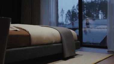 Güzel, sakin bir yatak odası, modern bir yatak odası ve pencereden bakıldığında büyüleyici bir kış manzarası.