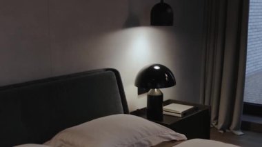 Şık ışıklandırma ve minimalist zarafetle tamamlanmış zarif bir dekor sergileyen sakin ve modern bir yatak odası.