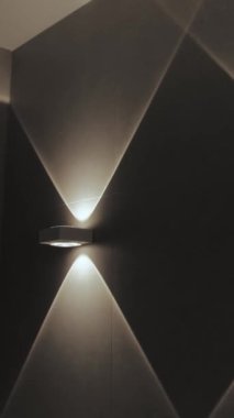 Dikey video. Zarif bir duvar, odanın dokulu yüzeyine çarpıcı ışık desenleri saçar.