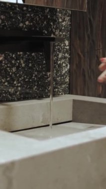 Zarif bir şekilde akan suyla minimalist bir tasarıma sahip güzel, gösterişli ve modern bir çeşme. Dikey video.