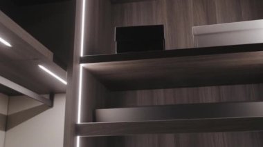 Modern bir iç mekanda çevre ışıklarıyla güzelce aydınlatılmış şık ahşap raflar.