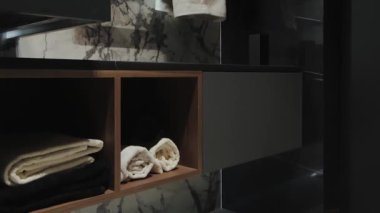 Burası lüks ortamlarda şık ve verimli bir havlu depolama çözeltisi sunan modern bir banyo.