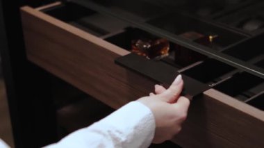 Çekmeceyi açan bir elin yakın çekimi, parlak tasarımı ve büyük işlevselliği vurguluyor.