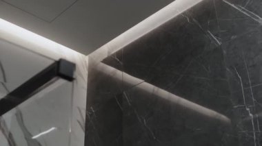 Cam ve mermerden yapılmış zarif bir kesişme banyodaki modern tasarım estetiğini gözler önüne seriyor.