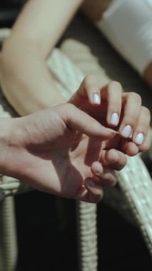 Açık havada birbirine dolanmış, sevgiyi, bağlantıyı ve rahatlığı sembolize eden iki elin yakın çekimi. Dikey video