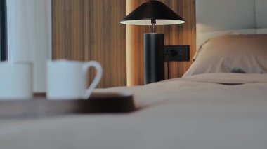 Bu sakin ve huzurlu yatak odasında şık bir lamba, kahve fincanları ve rahatlamak için mükemmel tonlar var.