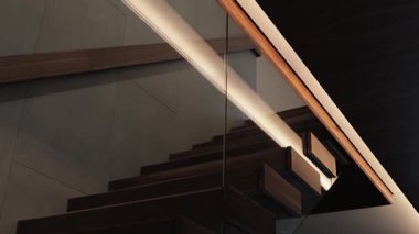 Parlak cam parmaklıklı zarif bir merdiven ve modern ışıklandırma, şık bir iç tasarım için ideal.