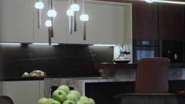 Modern tasarım, zarif ışıklandırma ve taze elmaların sergilendiği şık ve çağdaş bir mutfak.