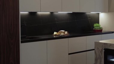 Bu çağdaş mutfak tasarımı, şık bir görünüm için minimalist dekorla birlikte gösterişli dolaplar sergiliyor.