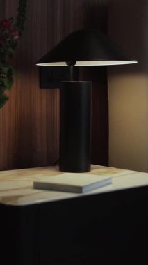 Parlak siyah bir lamba modern bir komodinin üzerine zarif bir şekilde konmuştur. Şık iç mekanları geliştirmek için mükemmeldir. Dikey video