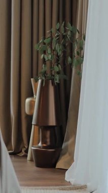Modern dekorda şık bir vazo ve zarif perdeler var, rahat ve davetkar bir ortam yaratıyor. Dikey video