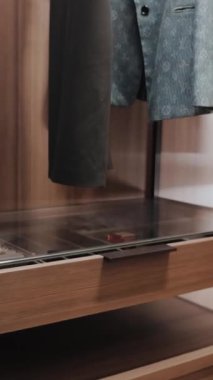 Kıyafet ve aksesuarların sergilendiği cam bir dolap. Lüks Modern Daire İçi. Dikey video. 4k video