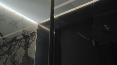 Bu şık banyo köşesinde zarif cam kapılar ve mermer duvarlar modern bir tasarım ve ambiyans sergiliyor.