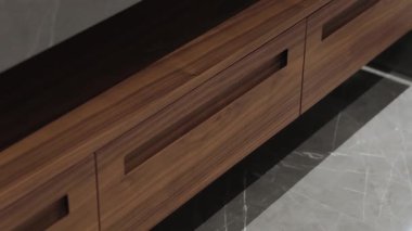 Bu şık ahşap dolapta modern görünüş için zarif saplarla tamamlanmış minimalist bir tasarım sergileniyor.