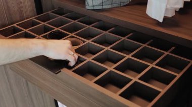 Bir adam dolabın kapısını açar ve çekmecelerin ahşap çekmecesine kemer koyar. Modern oturma odası iç tasarımı.