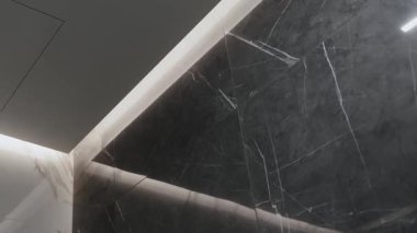 Modern ışıklandırmayla benzersiz bir şekilde vurgulanmış zarif, karmaşık koyu mermer desenli bir köşe.