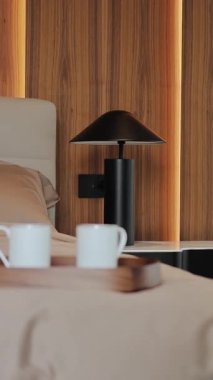 Bu modern yatak odasında minimalist bir estetik tasarım sergileniyor. Sıcak ahşap tonlar ve davetkar kahve fincanları var. Dikey video
