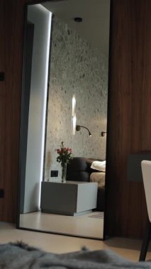 Modern çağdaş bir yatak odası şık bir minimalist mobilya tasarımıyla birlikte parlak bir ayna sergiliyor. Dikey video
