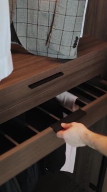 Modern dolap tasarımında yer alan pürüzsüz, parlak, kahverengi bir çekmeceyi dikkatlice açan bir elin yakından görüntüsü. Modern Daire İçi. Dikey video