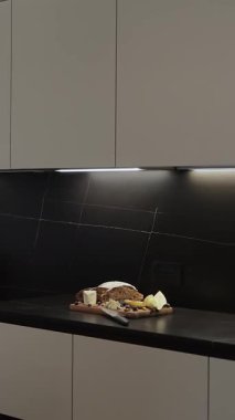 Pürüzsüz ve modern bir mutfak seti. Taze, kabuklu ekmeğin yanında güzel düzenlenmiş bir et tabağı sunuyor. Dikey video