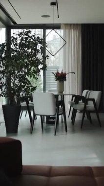  Dikey ekran: beyaz mermer bir masa ve sandalyeli modern bir oturma odası, zarif bitkiler ve şık mobilyalar sıcak, rahat bir atmosfer yaratır