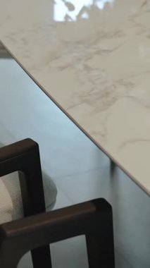 Lüks mermer bir yemek masasının yakın çekimi. Şık mermer masa üstü güzel bir şekilde parlak eşleştirilmiş. Dikey video 4k