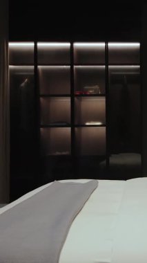  Dikey ekran: Modern bir yatak odasında, rahat bir tasarımı ve aydınlığı olan siyah bir gardırop. Lüks Modern Daire İçi. 4k