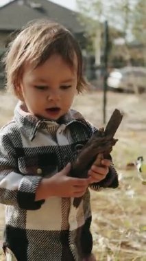  Dikey ekran: Bir çocuk oyun oynarken eğleniyor, sokakta gülümsüyor ve sonbahar sezonunda evinin yakınındaki şenlik ateşi için odun topluyor.