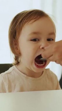 Bir çocuk sıcak bir evde annesiyle birlikte lezzetli bir yemekten zevk alır. Dikey video.