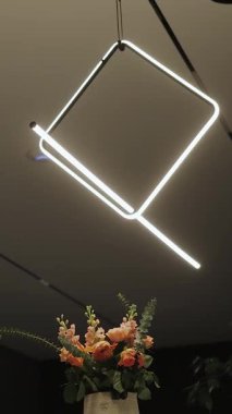 Zarif ve modern bir aydınlatma armatürü şaşırtıcı güzellikteki çiçeklerin üzerine asılmış.