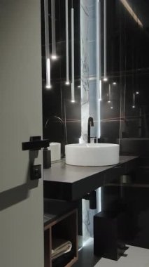  Dikey ekran: Modern banyo tasarımında parlak siyah bir musluğun yer aldığı şık ve zarif yuvarlak bir lavabo.
