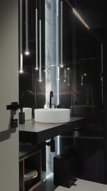 Zarif bir lavabosu ve sıcak ışıklandırması olan minimalist bir banyo huzurlu ve rahatlatıcı bir atmosfer yaratıyor. Dikey video