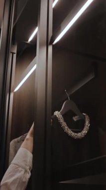Kadınların eli gardıroba elbise asar, şık, koyu renk bir gardırop. Dikey video 4k